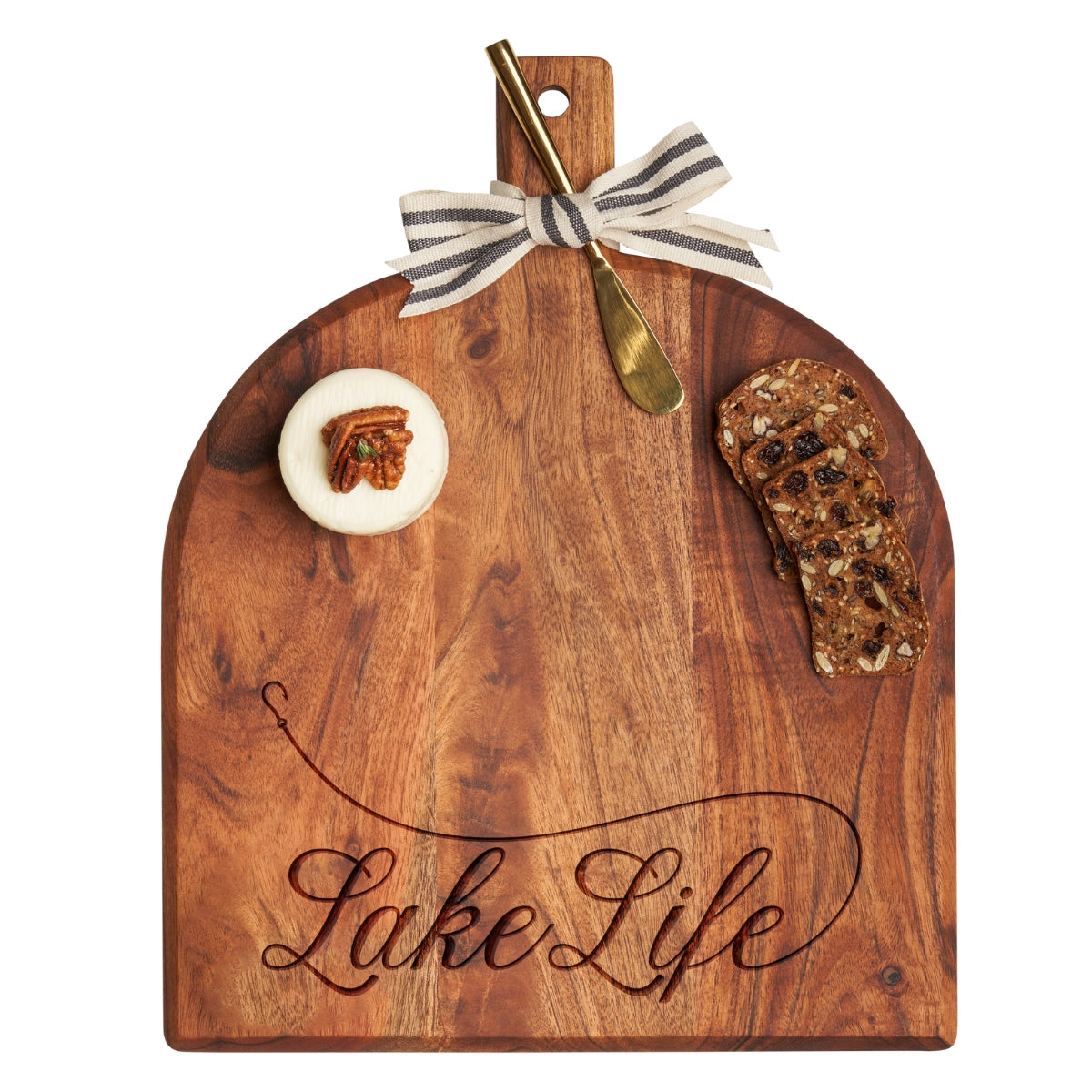Wooden cutting board with 'Lake Life' engraving, accompanied by a gold knife and food items on a white background.