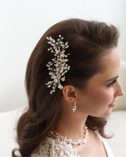 Woman wearing a decorative hairpiece and earrings with a white background