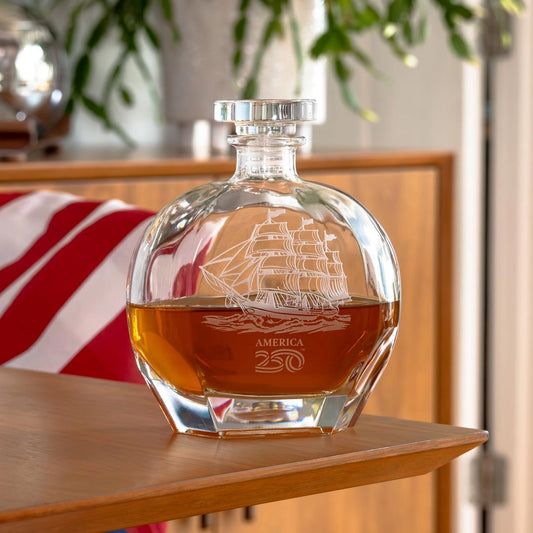 Glass decanter with ship engraving on a wooden surface