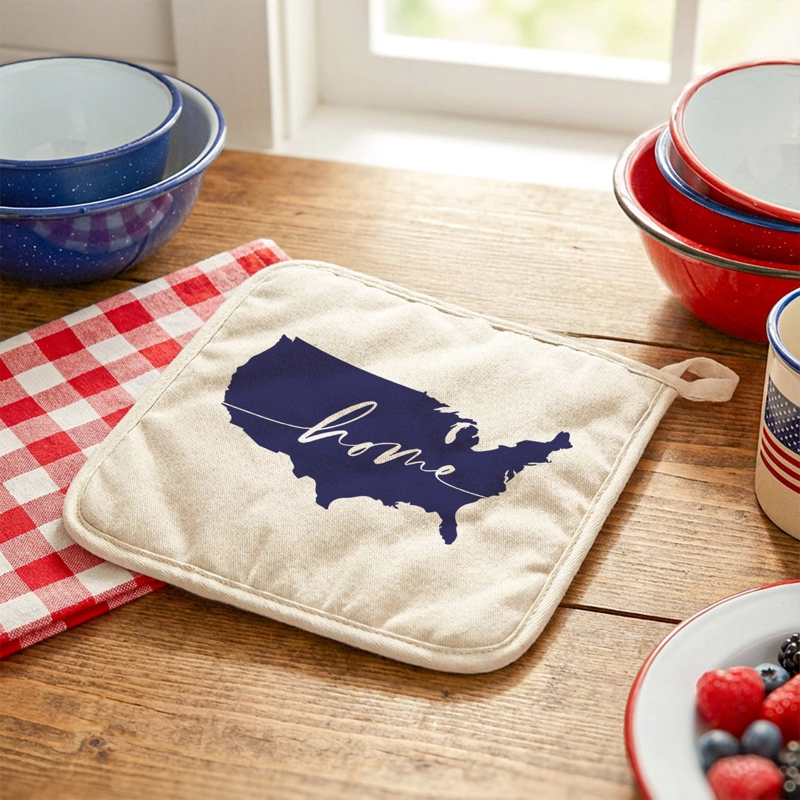 Potholder with USA map and 'home' text on a wooden table with kitchen items.