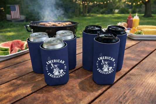 Navy blue can coolers with 'American Excellence' design on a wooden table outdoors.