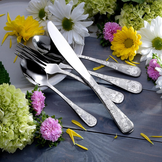 Silver cutlery set with floral decorations on a dark surface