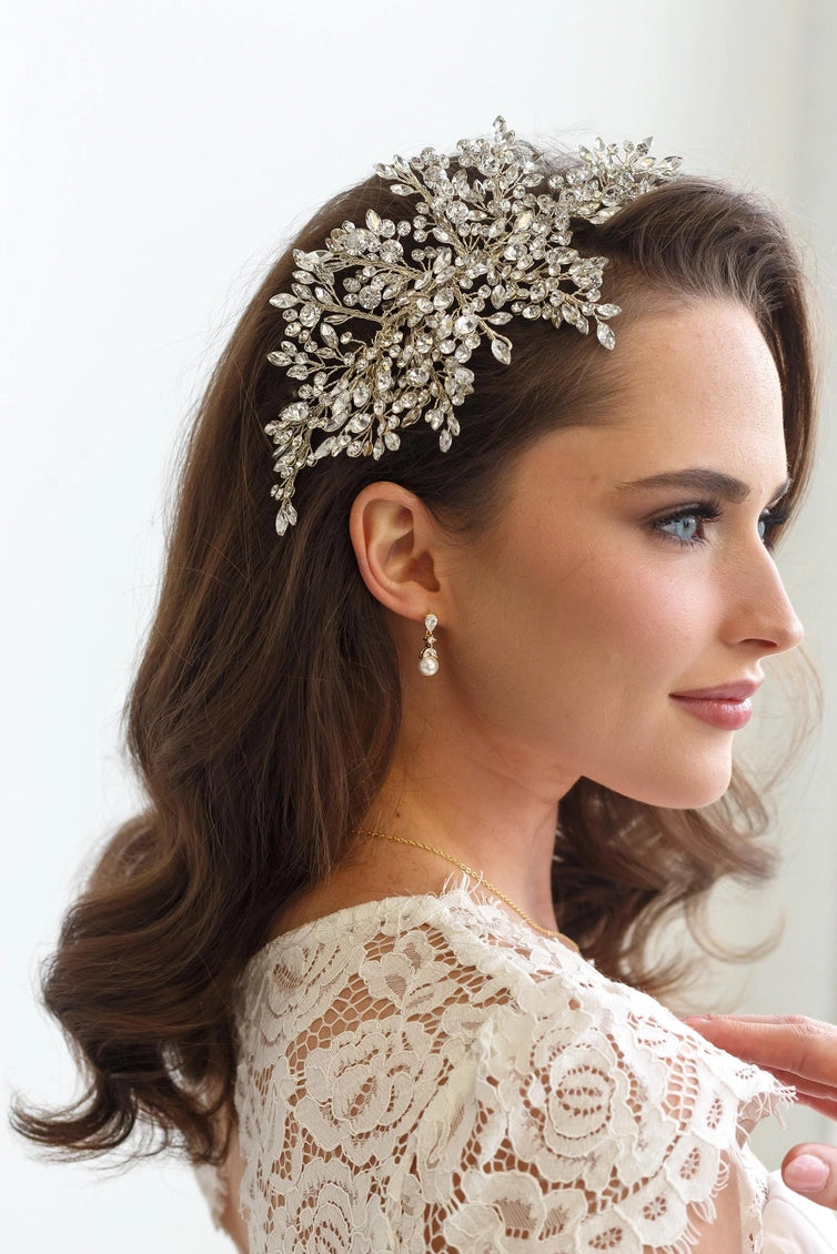 Woman wearing a decorative headpiece with a white lace garment on a plain background