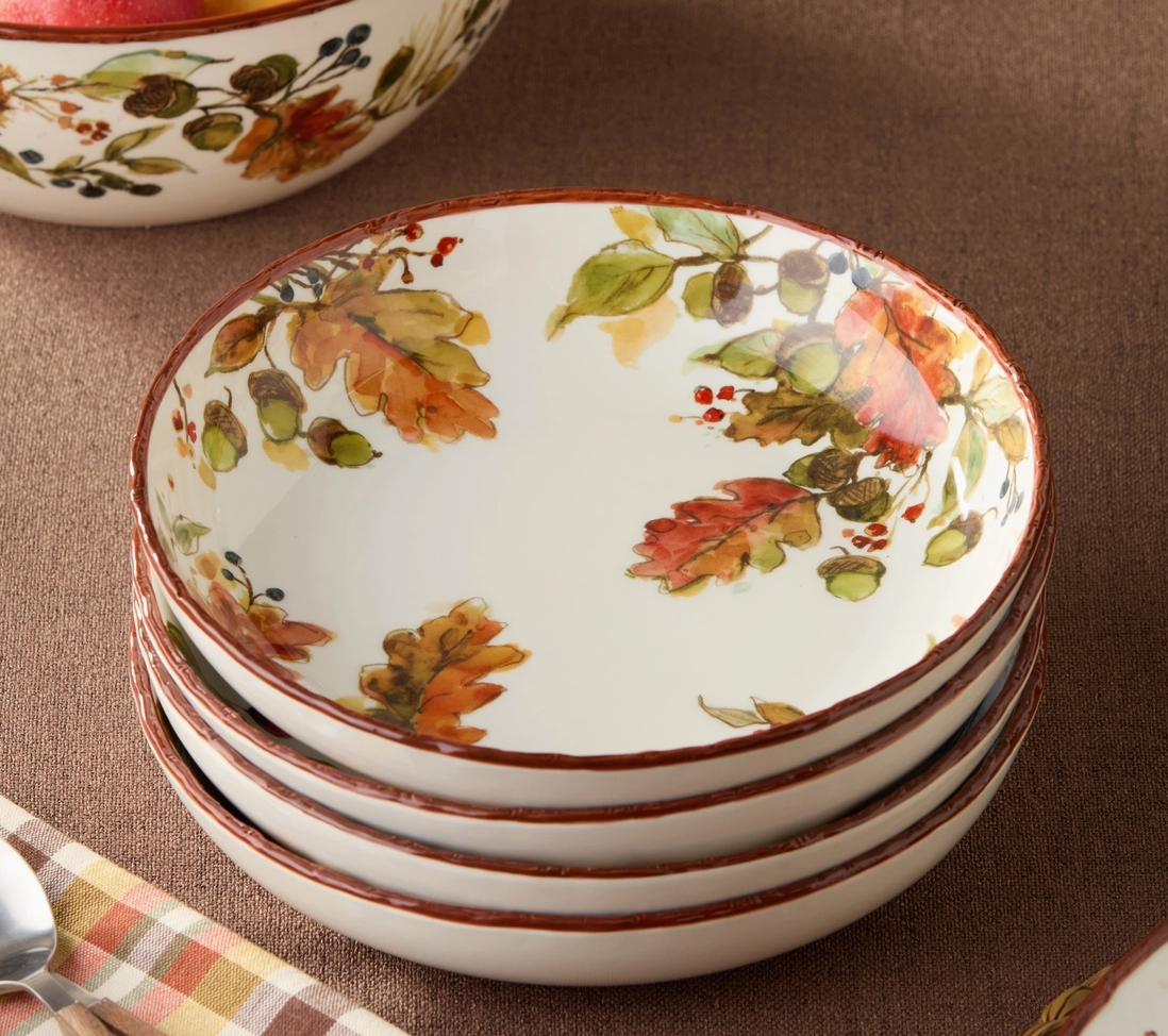Stack of ceramic plates with autumn leaf design on a brown surface