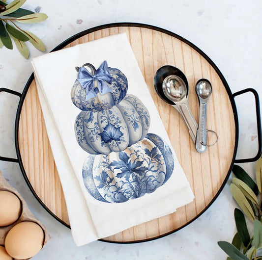 Tea towel with blue floral design on a wooden board with measuring spoons and eggs.