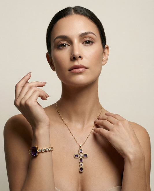 Woman wearing a gold necklace with a cross pendant and amethyst stones on a beige background