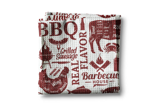 Woven towel with barbecue-themed design on a white background