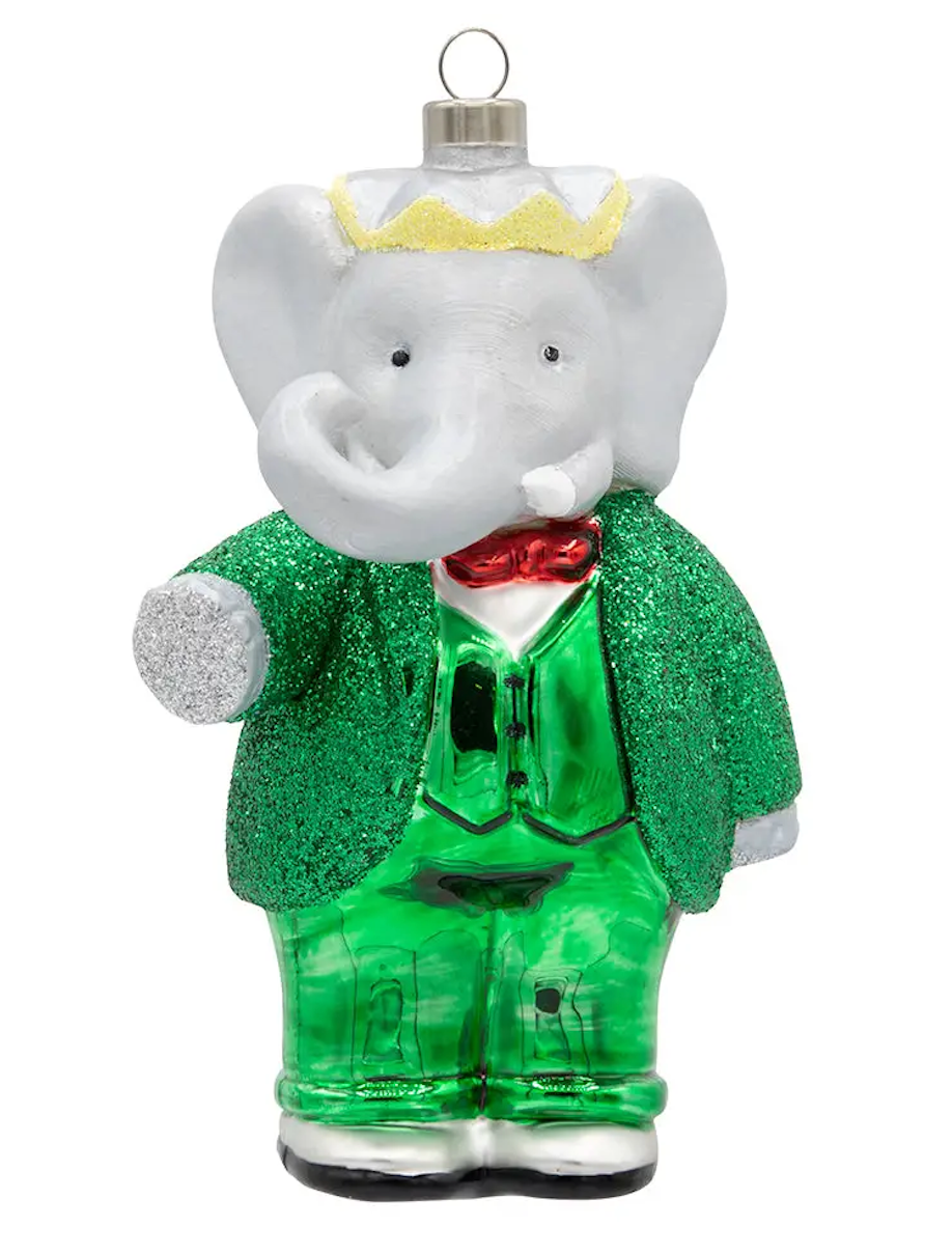 A glass elephant Christmas ornament dressed in a sparkling green suit with a red bow tie, white gloves, a yellow glitter crown, and a silver hanging loop, shown on a plain white background.