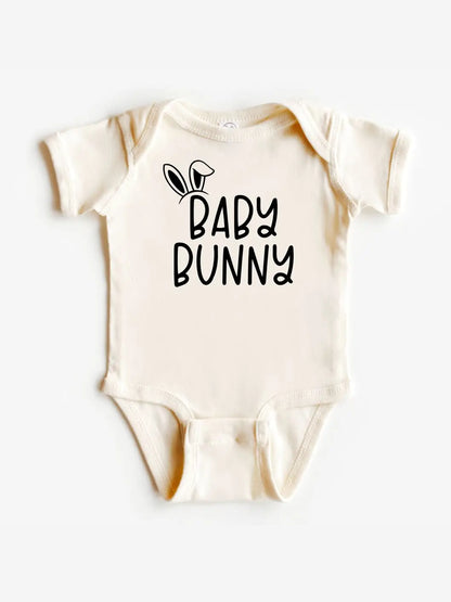A cream-colored baby bodysuit with a black graphic print that reads 'BABY BUNNY' with bunny ears, displayed flat against a light gray background.