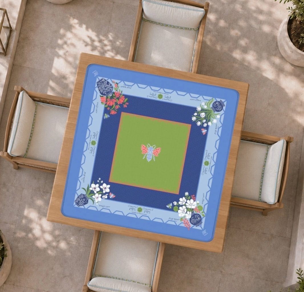 Bams & Bees Mahjong mat displayed on a square game table with periwinkle blue border, navy frame, green center, florals and chinoiserie details.

