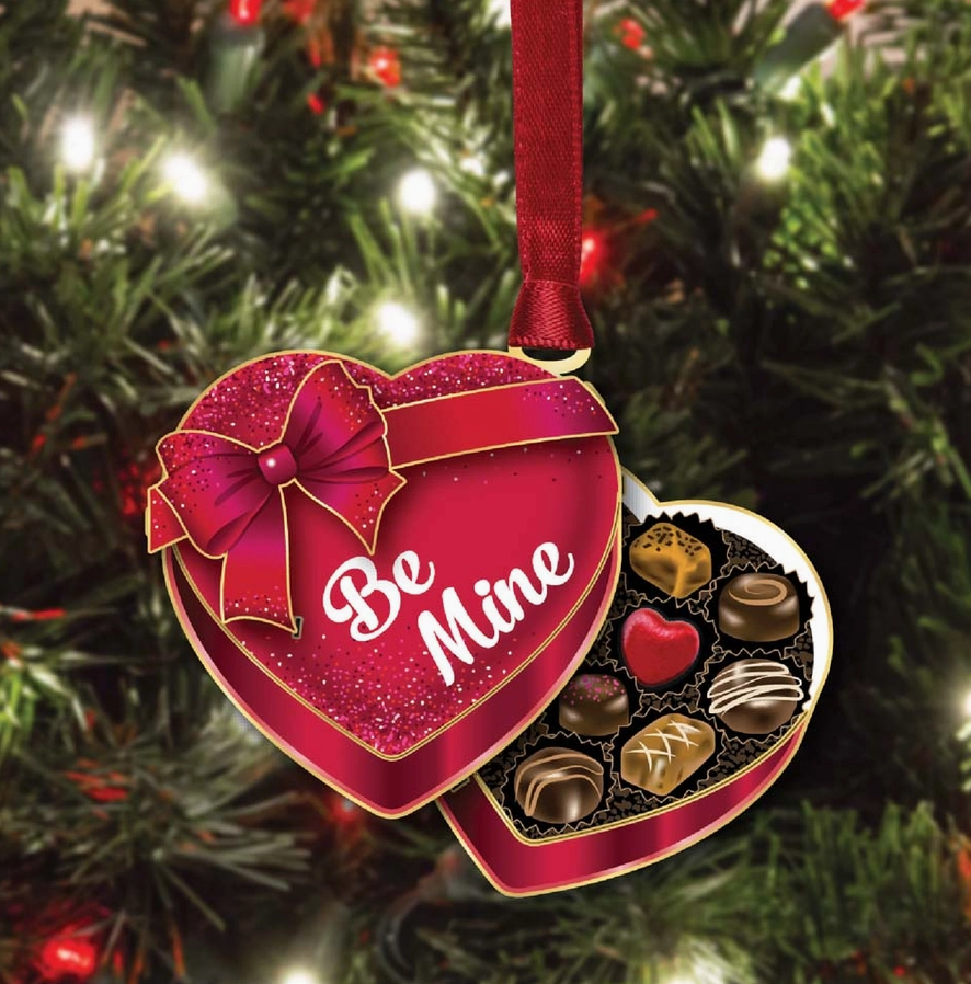 Heart-shaped chocolate box ornament with 'Be Mine' text on a Christmas tree.