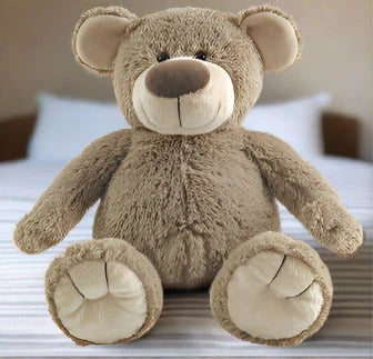 Brown teddy bear sitting on a bed