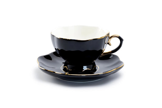 Black teacup and saucer with gold accents on a white background