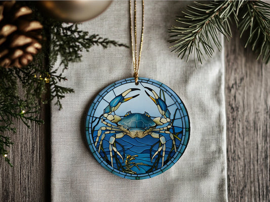 Decorative ornament with blue crab design on a wooden surface with pine branches.