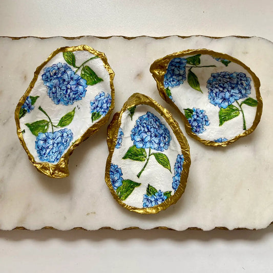 Decorative oyster shells with blue hydrangea patterns on a marble surface