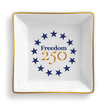 White decorative plate with blue stars and 'Freedom 250' text on a white background