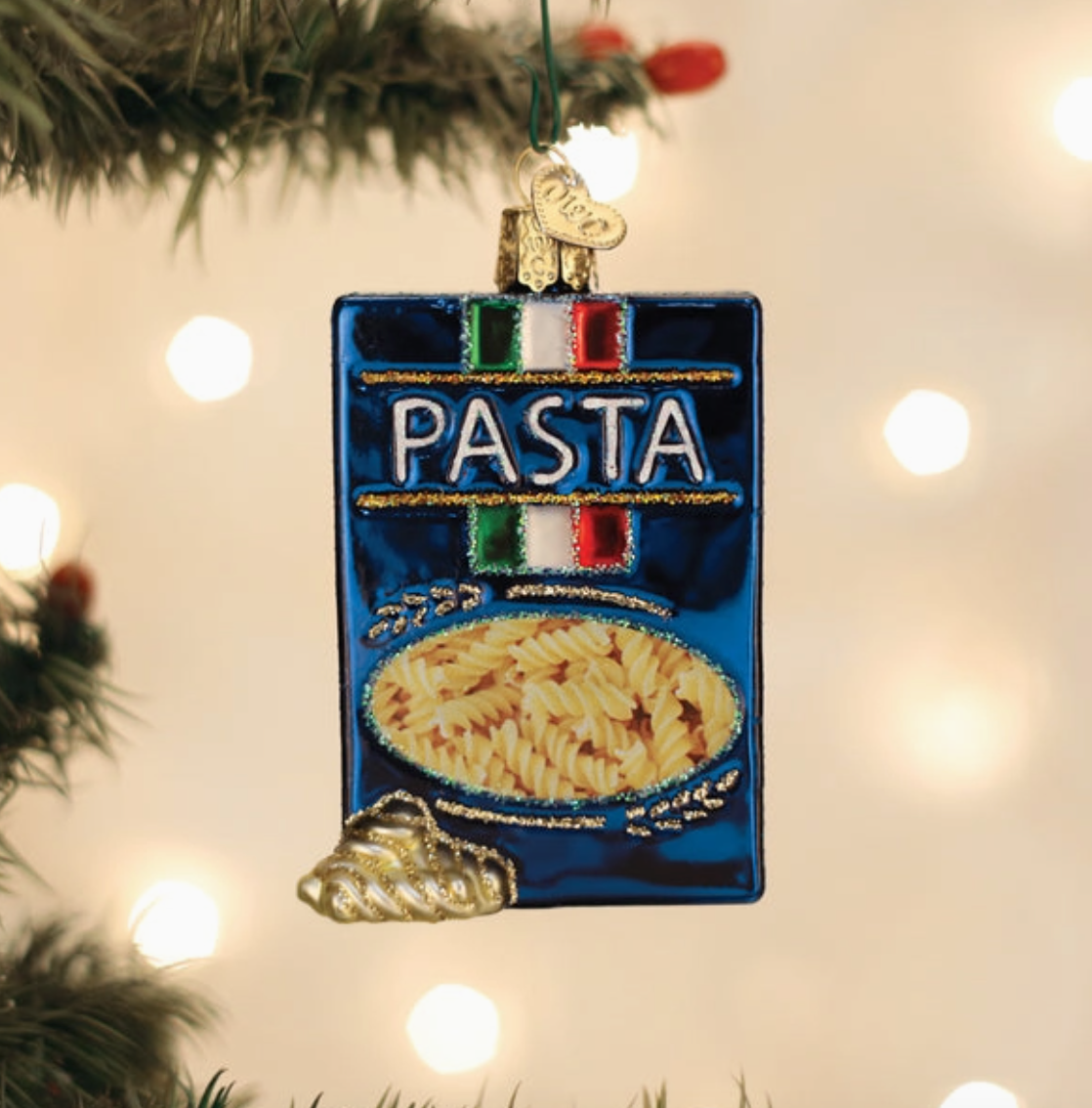 Blue box of pasta glass Christmas ornament with Italian flag details and spiral pasta hanging on a Christmas tree