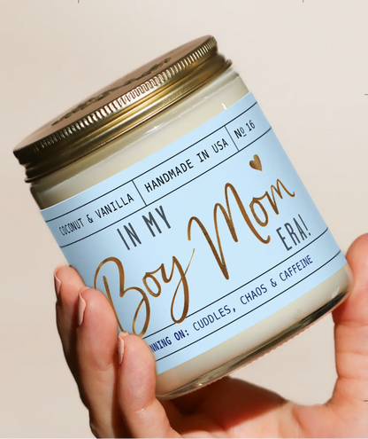 Candle jar with a label reading 'In My Boy Mom Era!' held by a hand, with a beige background.