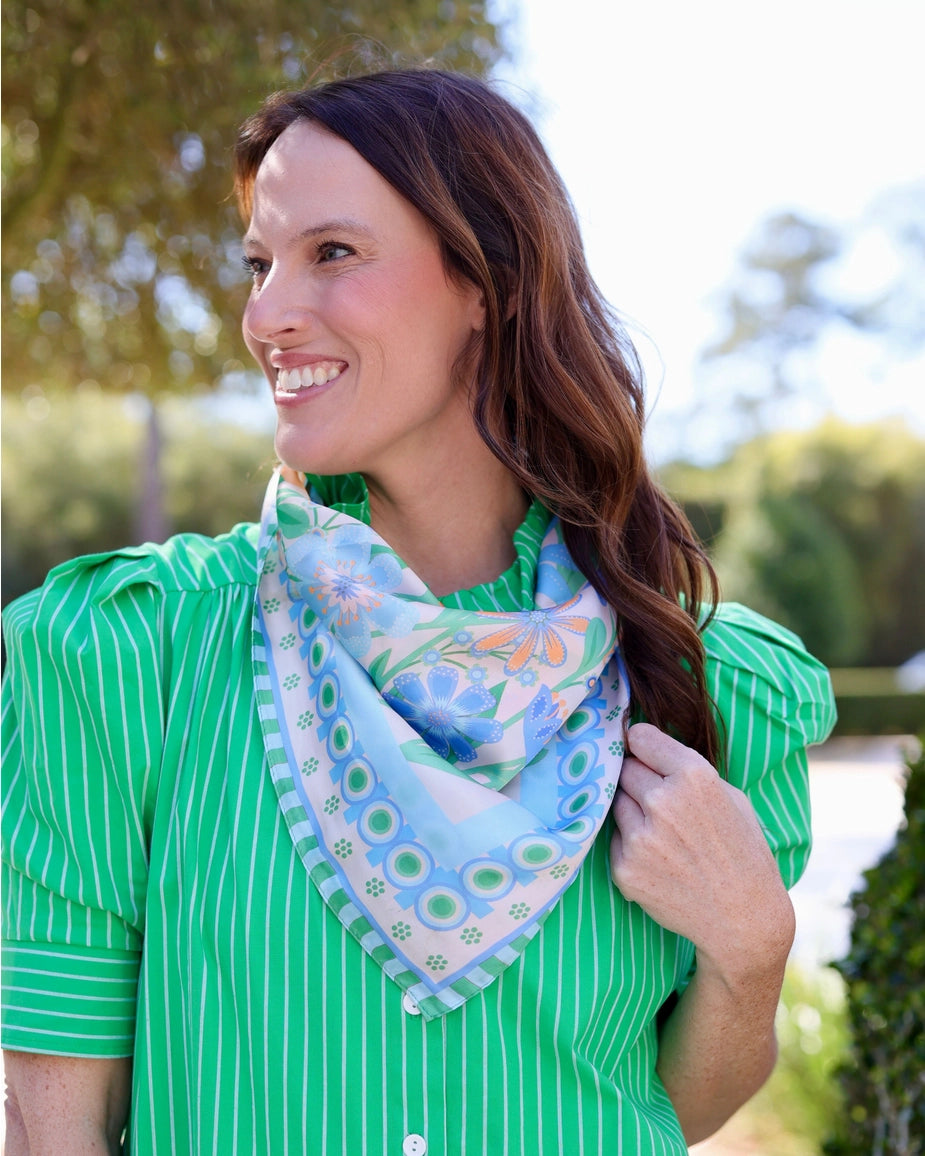 Woman wearing a green shirt with a floral scarf outdoors