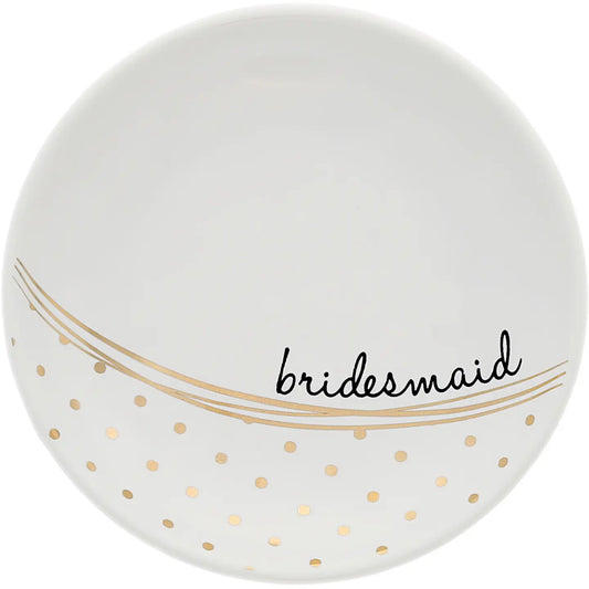 A white round ceramic plate with gold polka dots and gold wavy lines, featuring the word 'bridesmaid' in black script across the lower half.