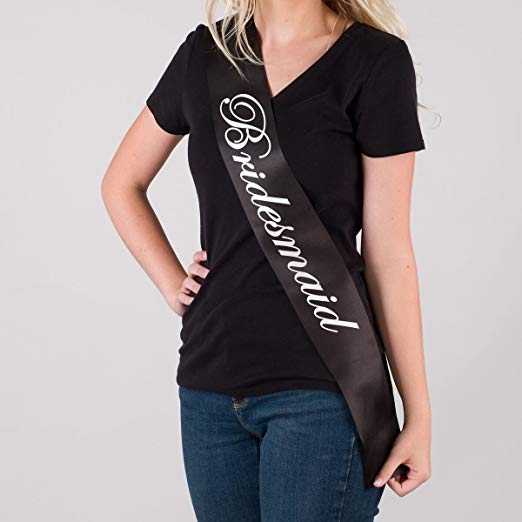 Person wearing a black 'Bridesmaid' sash on a plain background