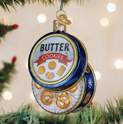 Blue butter cookies tin glass Christmas ornament opened to reveal assorted golden cookies hanging on a Christmas tree