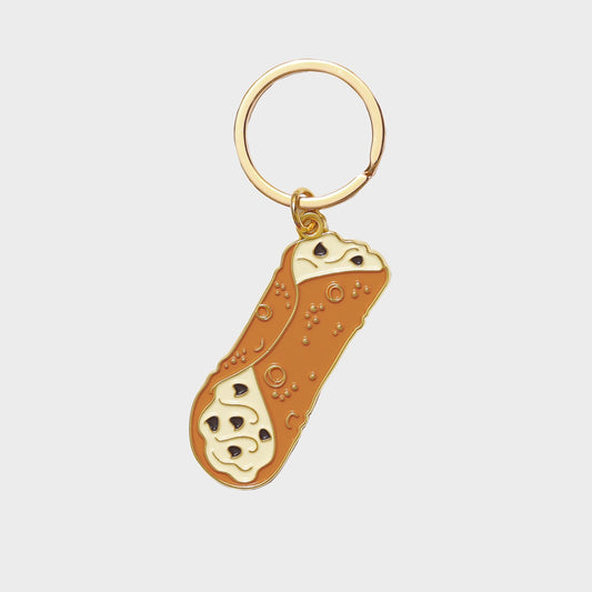 Keychain shaped like an italian cannolo  dessert on a light gray background