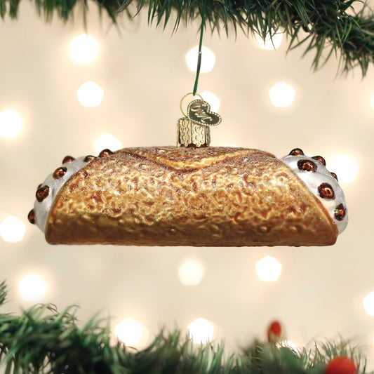 Decorative Christmas ornament shaped like a cinnamon roll hanging on a tree with lights in the background.