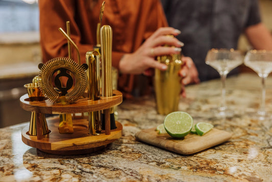 Bartending setup with bar tools and ingredients on a marble countertop.