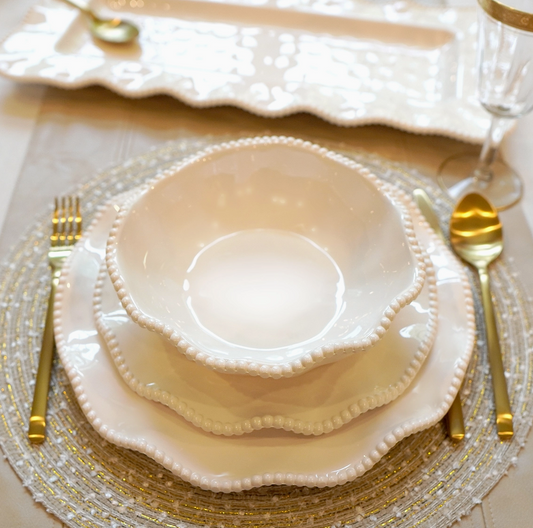 Perlette cream melamine bowl layered with matching dinner and salad plates on elegant table with gold flatware