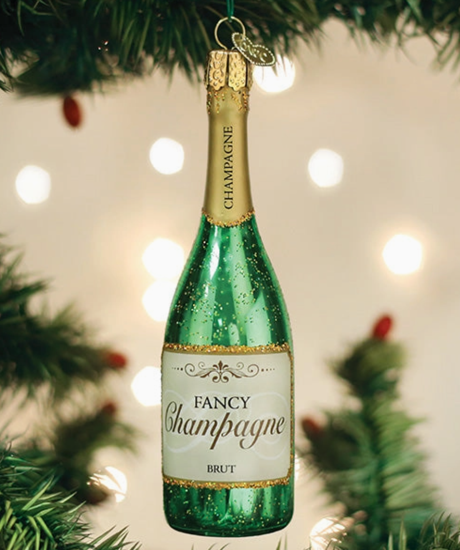 Green champagne bottle glass Christmas ornament with Fancy Champagne Brut label and sparkling gold details hanging on a Christmas tree