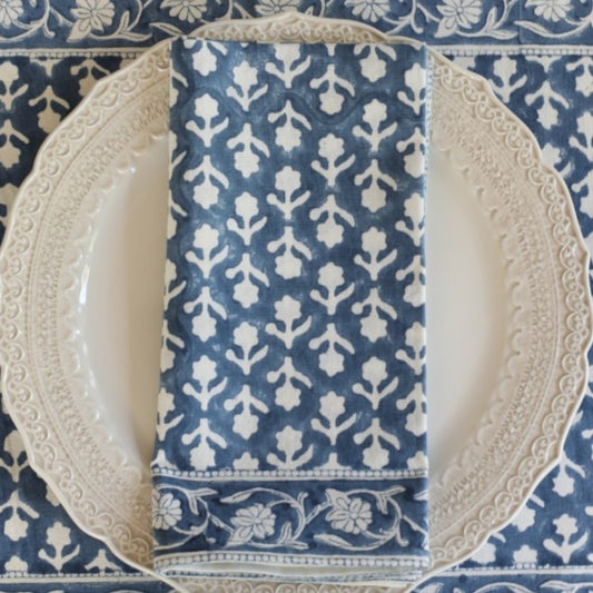 Blue and white patterned napkin on a decorative plate with a blue and white floral tablecloth.