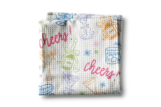 Waffle-textured kitchen towel with colorful 'Cheers!' and drink-related graphics on a white background