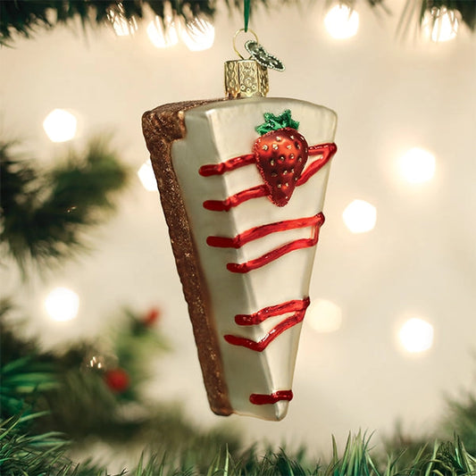 Decorative Christmas ornament shaped like a strawberry shortcake on a tree with lights in the background.