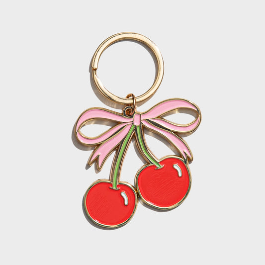 Keychain with red cherries and a pink bow on a light gray background
