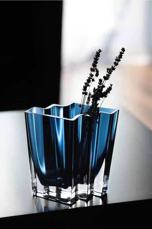 Blue glass vase with dried lavender on a reflective surface