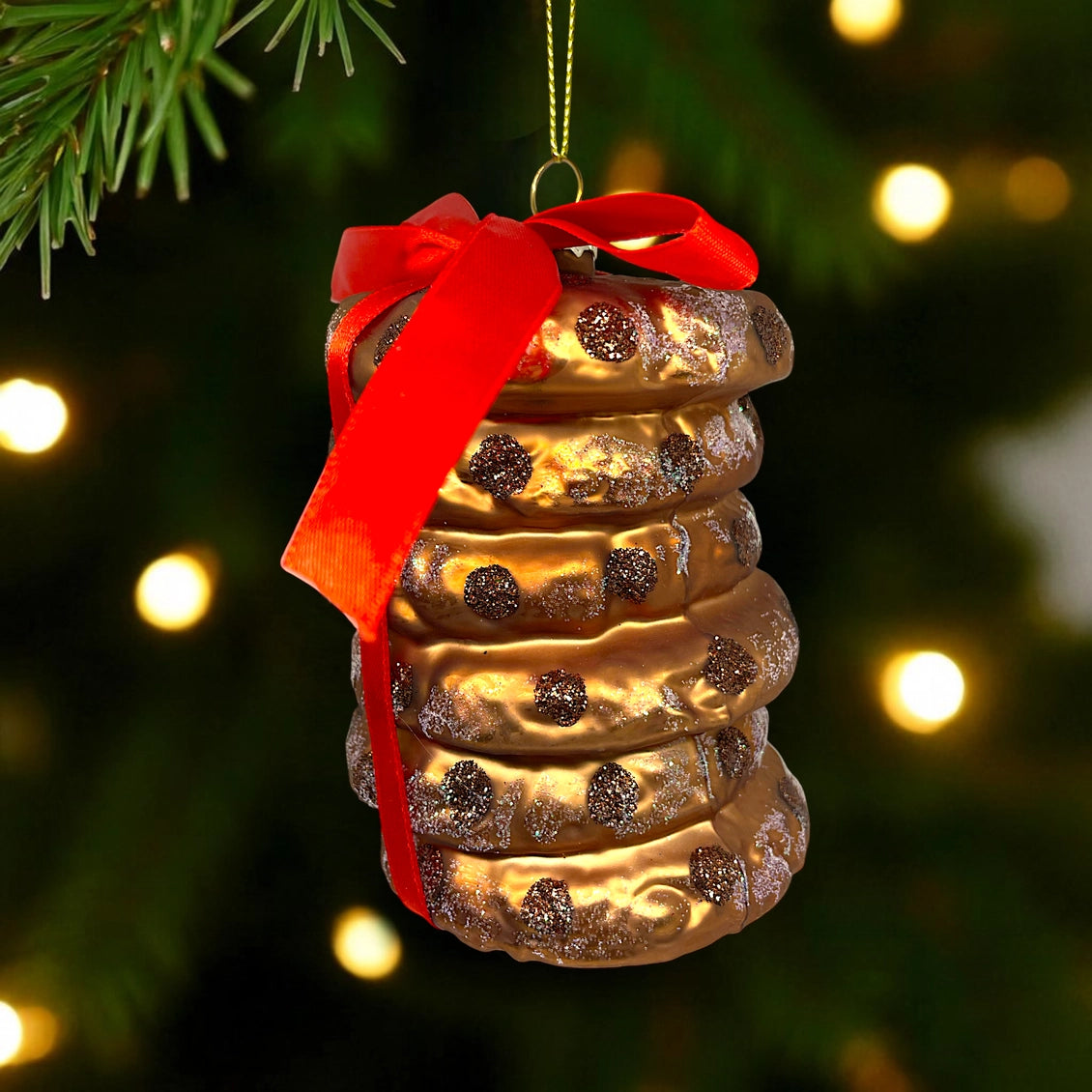 An image depicting a stack of chocolate chip cookies wrapped with a red velvet bow.