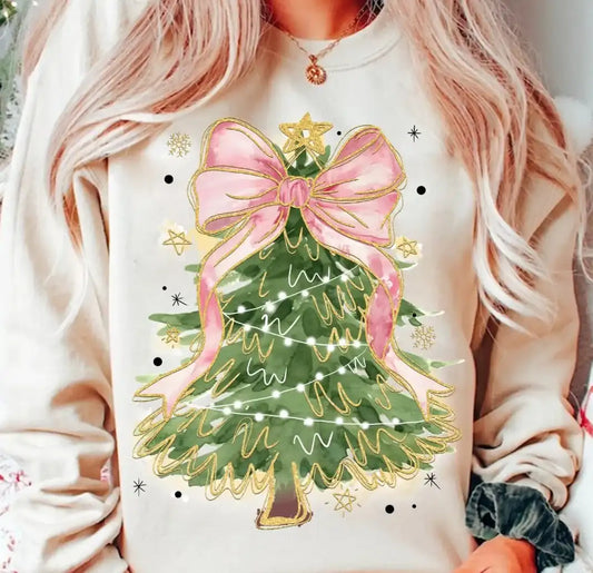 Person wearing a sweatshirt with a Christmas tree design featuring a pink bow.