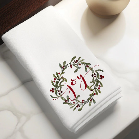 Folded white towel with 'Joy' design on a white surface