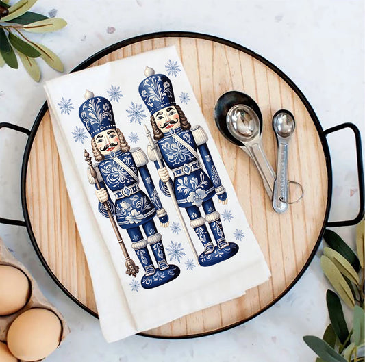 Tea towel with nutcracker design on a wooden board with measuring spoons and eggs.