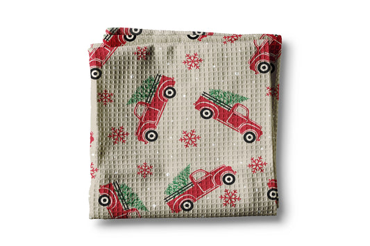 Folded fabric with red truck and Christmas tree pattern on a beige background