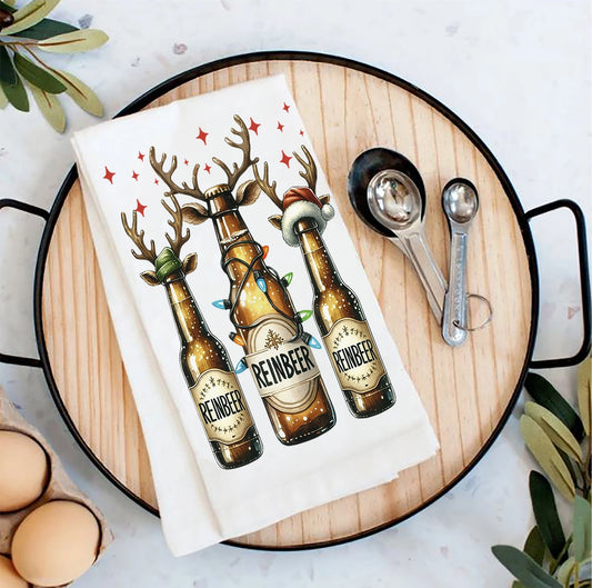 Tea towel with reindeer-themed beer bottles on a wooden board with measuring spoons and eggs.
