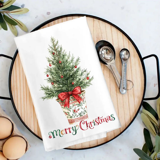 Decorative towel with Christmas tree design on a wooden board with measuring spoons and eggs.