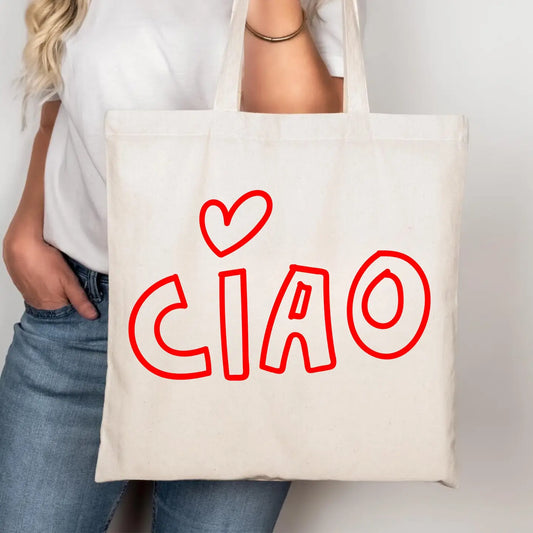 A person wearing a white t-shirt and blue jeans holds a cream-colored canvas tote bag with the word 'CIAO' and a heart drawn in red outline.