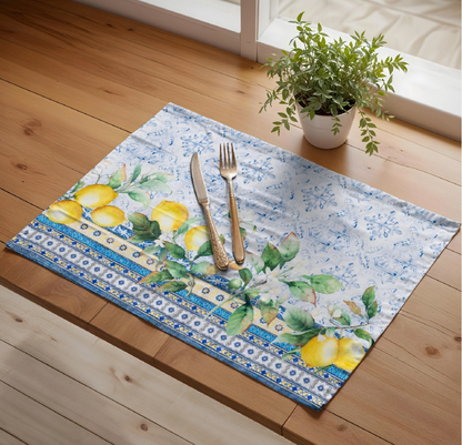 Decorative placemat with lemon design on a wooden table with cutlery and a plant.