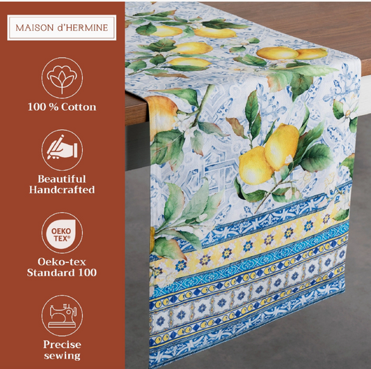 Tablecloth with lemon design on a wooden table, featuring branding and certification details.