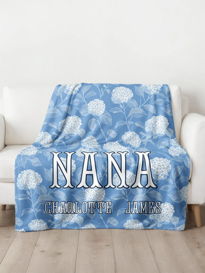 Blue floral blanket with 'Nana' and 'Charlotte James' text on a white couch.