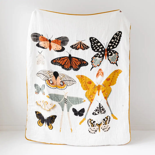 A white muslin blanket featuring a collage of various colorful butterfly and moth illustrations, finished with a thin mustard yellow border, shown against a plain white background.