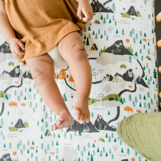 Baby legs on a play mat with nature-themed design