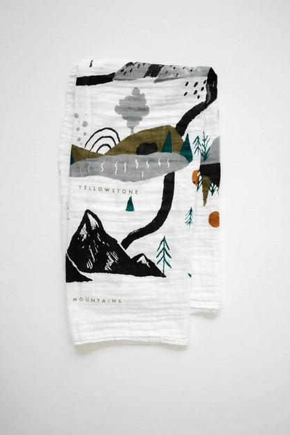 Folded blanket with nature-themed design on a white background